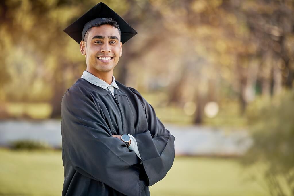Recent law school graduate wearing a cap and gown standing confidently after completing legal studies