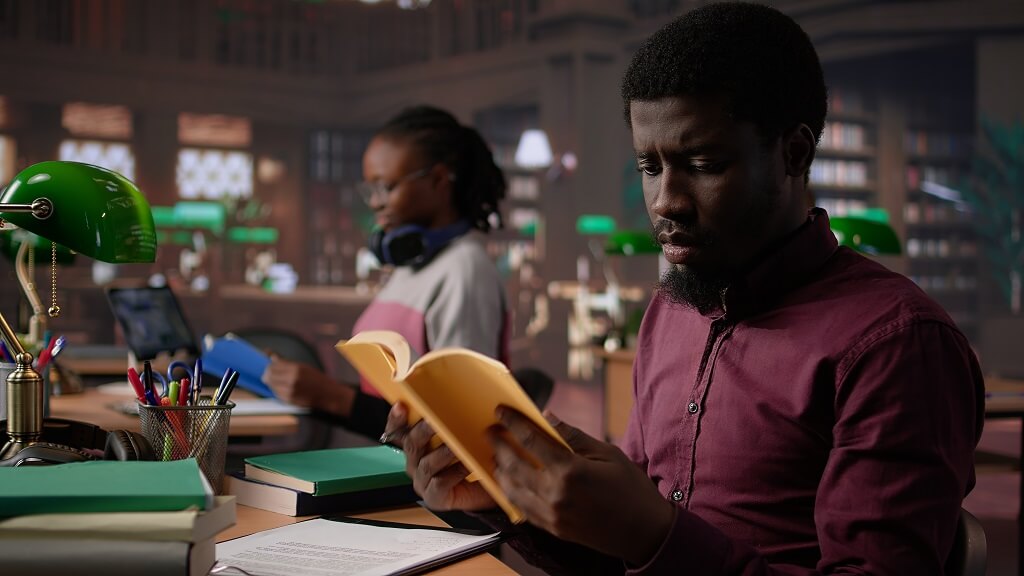 Law student holding a stack of legal textbooks inside a classroom while preparing for demanding coursework