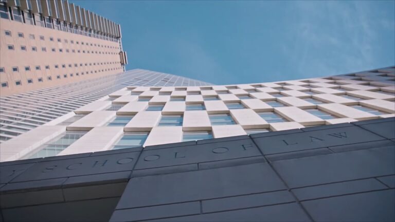 Upward view of a modern law school building with a blue sky background, showcasing a contemporary design