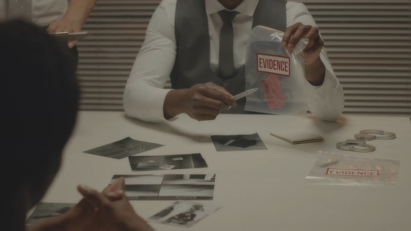 Officer showing labeled evidence photos during an interview in a police station