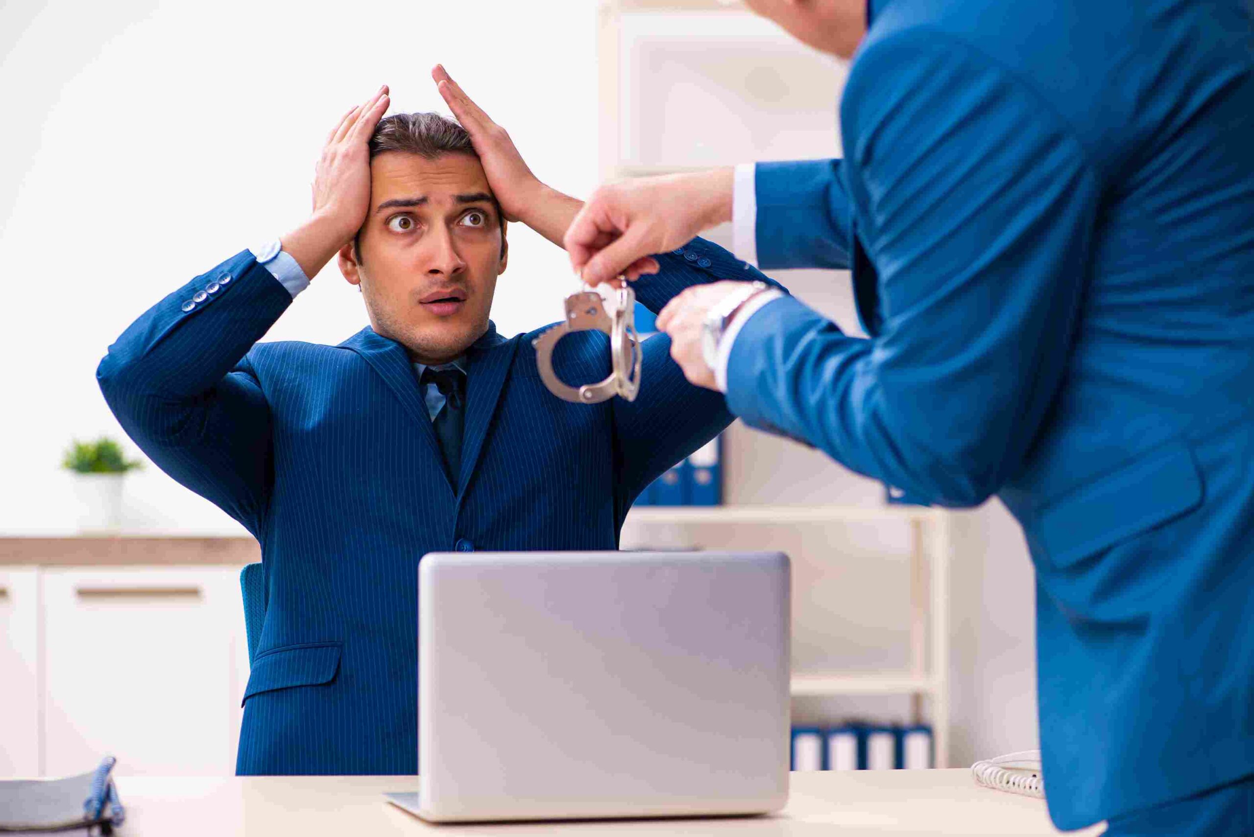 Man looking shocked as another person holds handcuffs during an arrest
