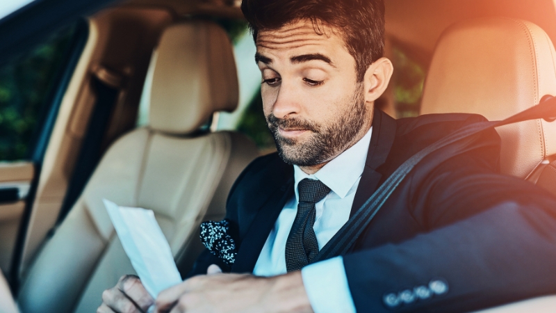 Driver sitting in a car reading a traffic ticket after being pulled over