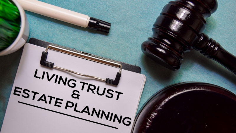 Clipboard labeled “Living Trust and Estate Planning” next to a judge’s gavel on a desk