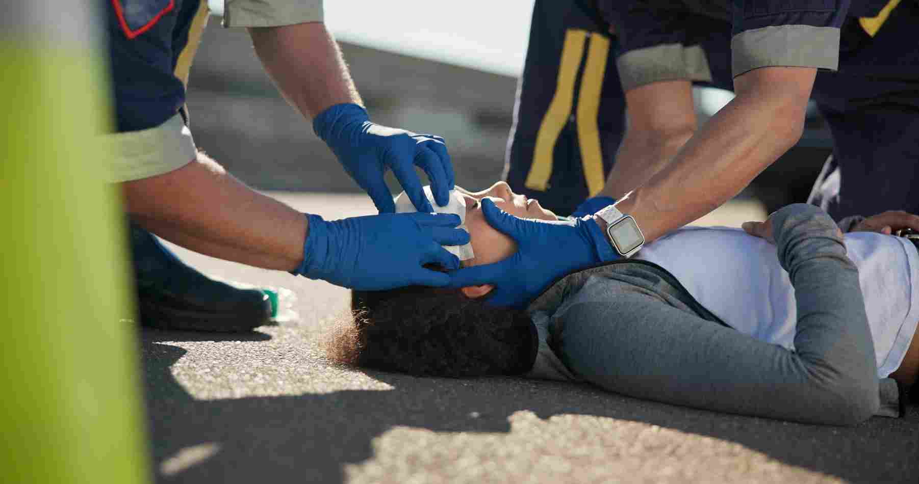 Emergency responders providing medical care to an injured person lying on the road after an accident