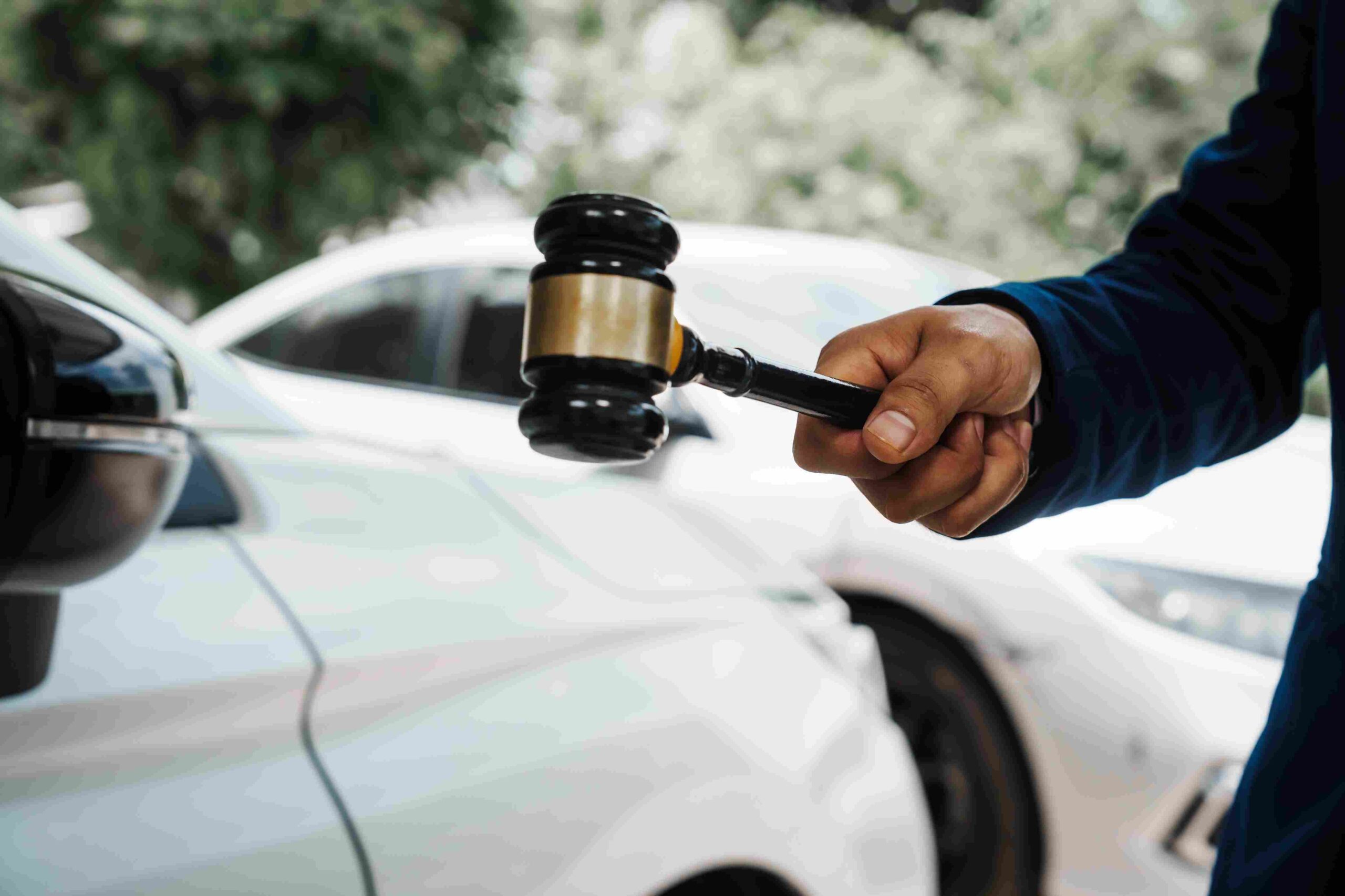 Close-up of a judge’s gavel held in front of parked cars