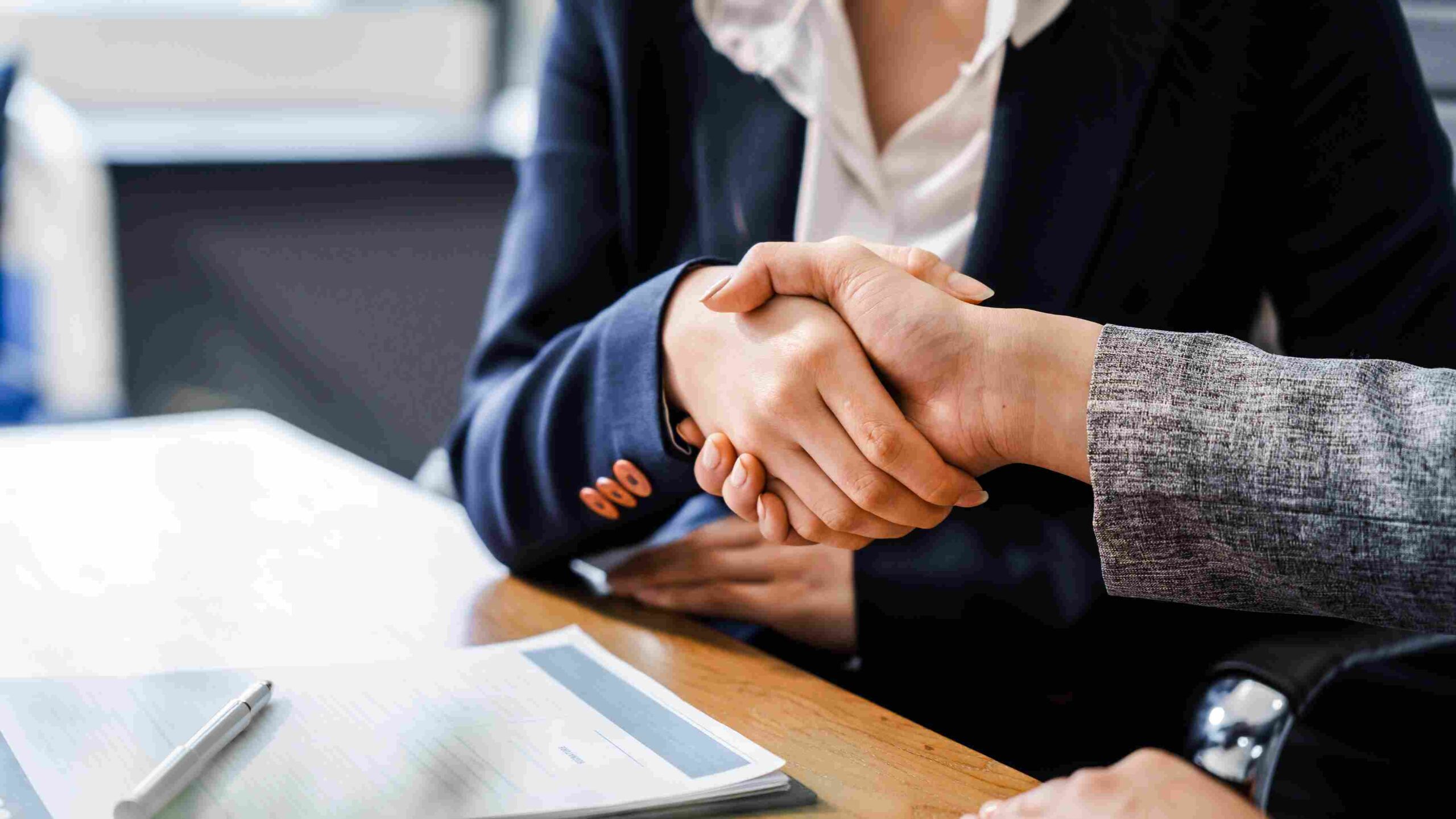 Two people shaking hands across a desk during a legal consultation