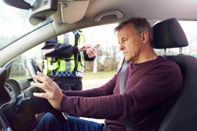 Man sitting in the driver’s seat during a traffic stop while a police officer stands outside the car