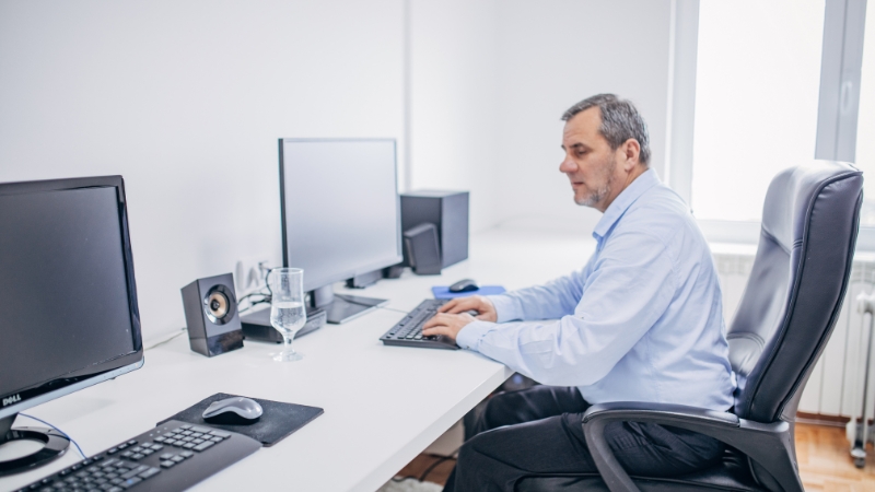 Employee working at a desk on a company work computer in an office environment