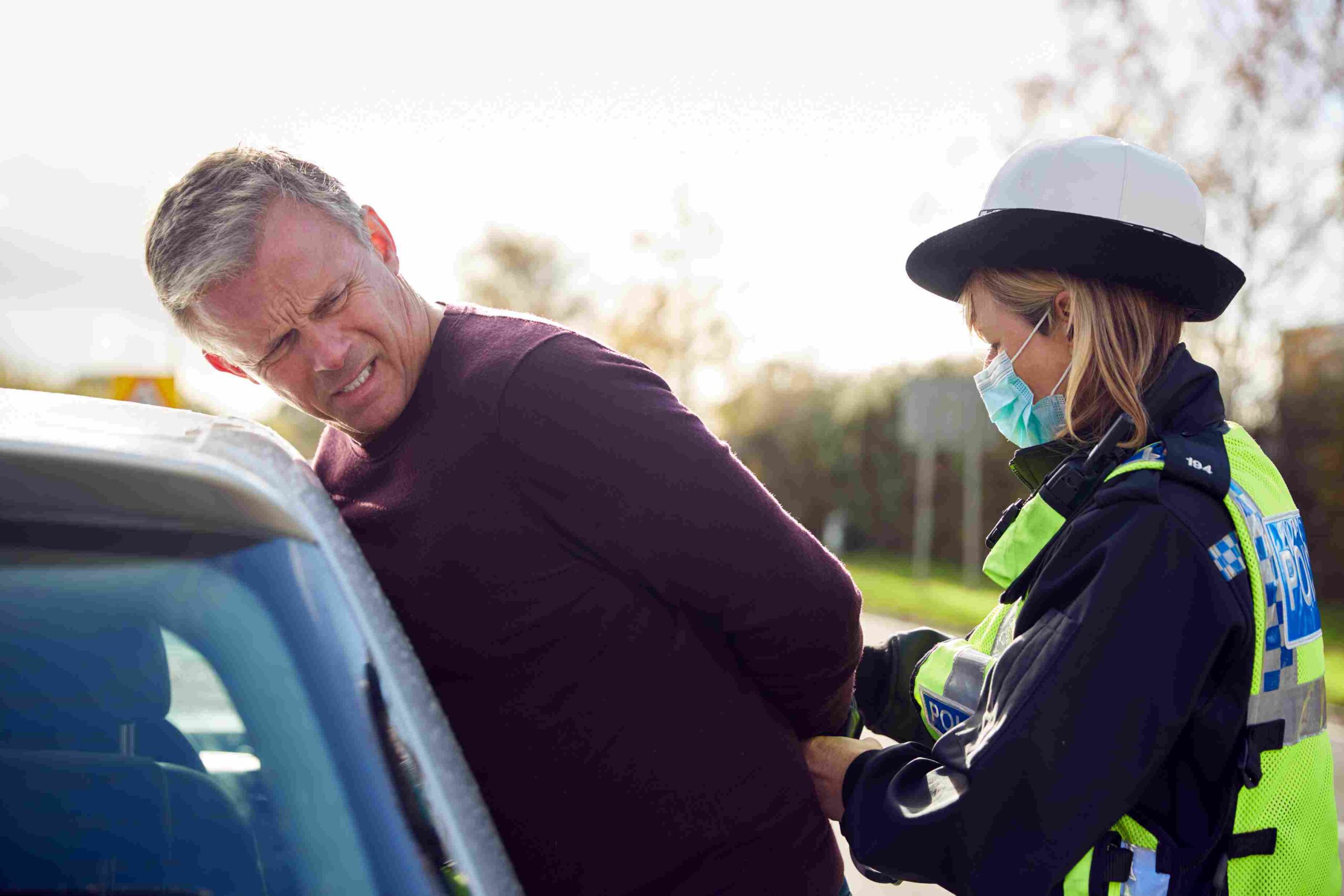 Police officer placing a man in handcuffs during a roadside arrest