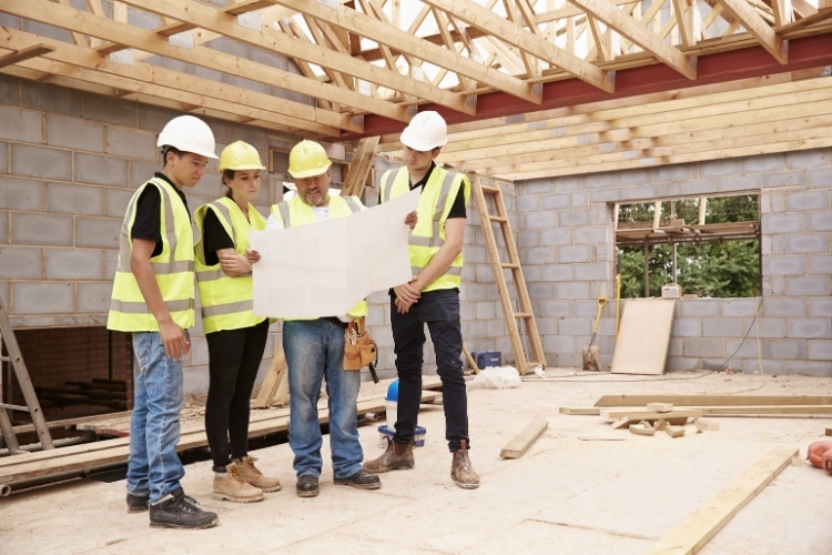Construction team reviewing building plans inside a partially completed structure.